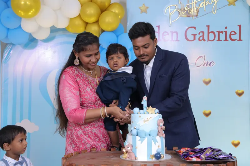 Parents cutting a first-birthday cake with their son